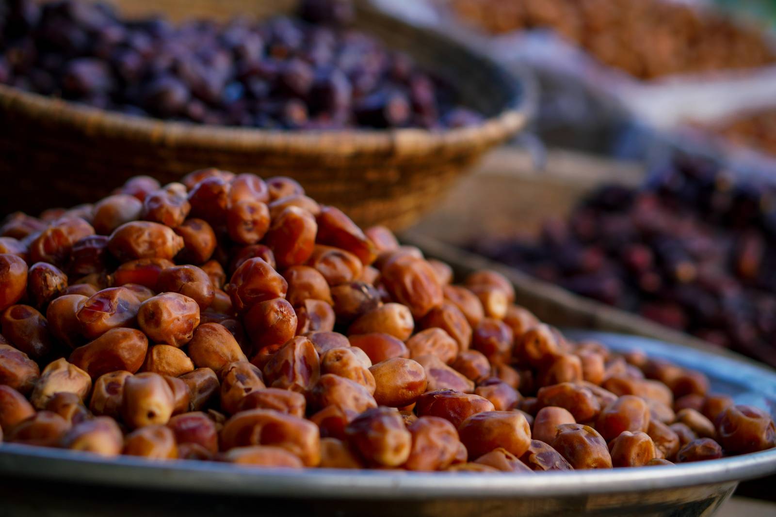 Fresh and dried dates piled in trays and baskets at a market.