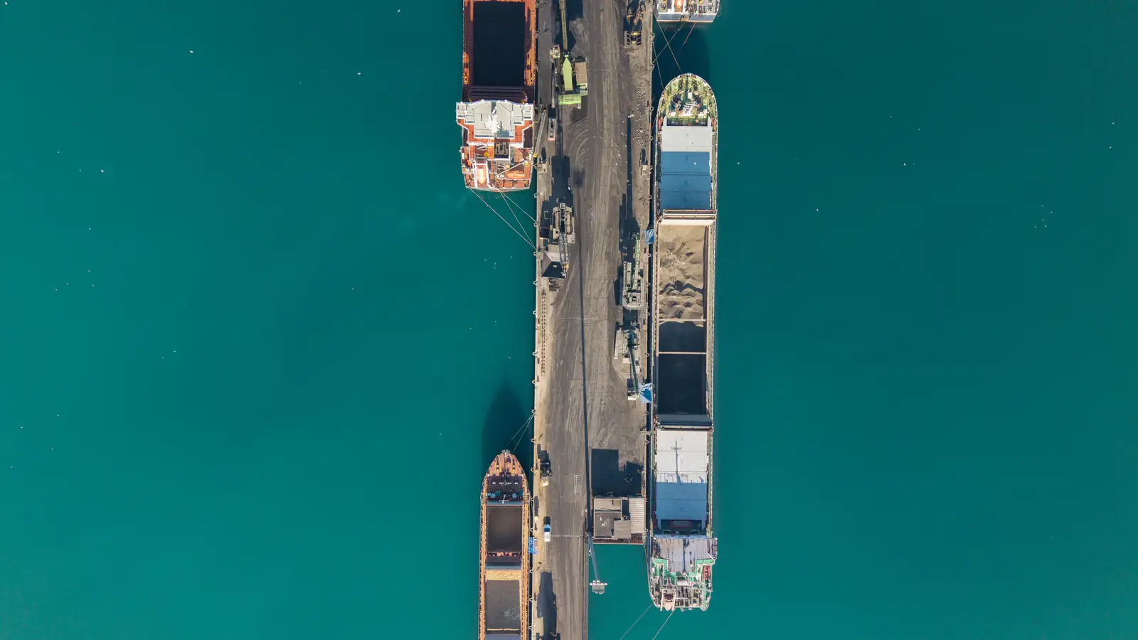Bulk carriers moored alongside a pier, seen from directly above.