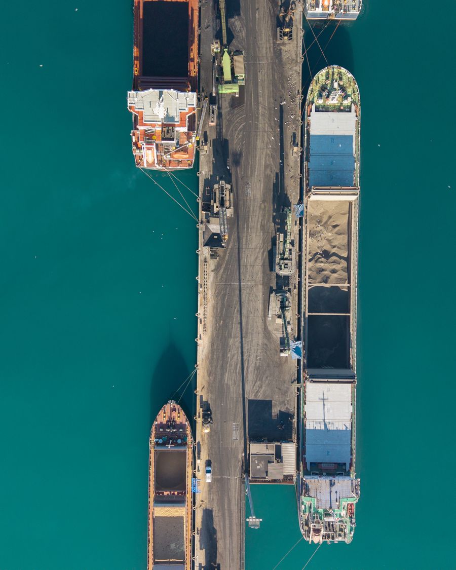 Bulk carriers moored either side of a pier, seen from above.